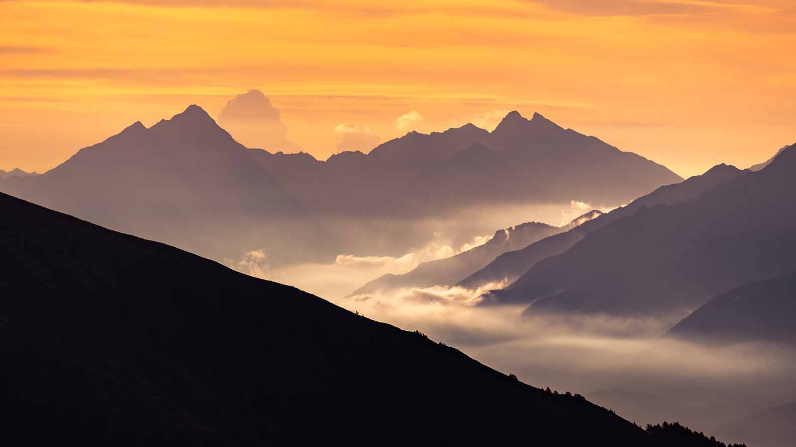 Picture of a mountain range with some low fog and clouds